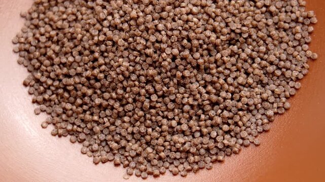 Dry gluten-free buckwheat couscous granules in brown kitchen bowl. Vegetarian diets ingredient. Top view. Rotation