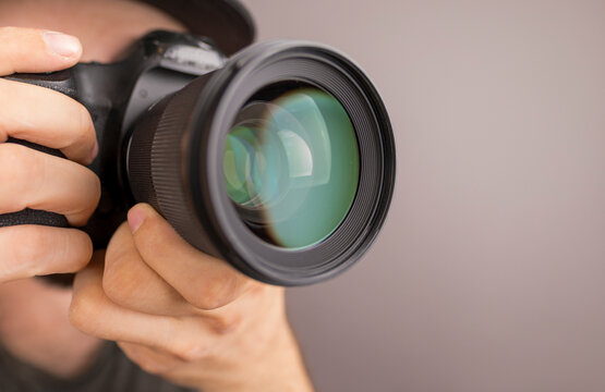 A photographer's eye looking through a camera lens, with hands holding the DSLR ready to capture a m