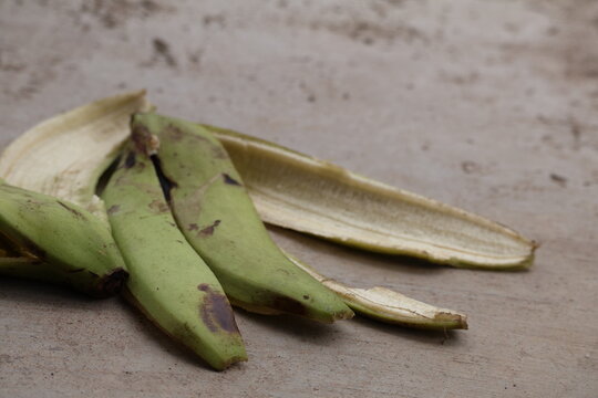 Green Ambon banana peel resting naturally on earthy ground