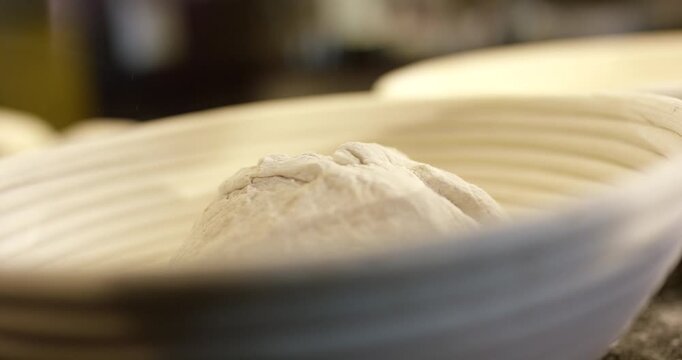 Chef in professional uniform preparing fresh bread dough on kitchen counter with flour