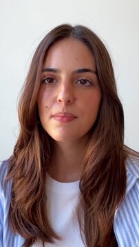 Close-up of a young brunette woman speaking directly to the camera, showcasing various emotions from happy and enthusiastic to serious and pensive, isolated on a white background