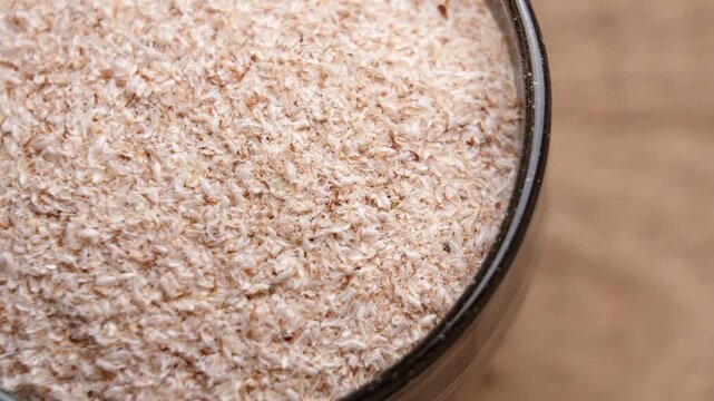Organic psyllium husk plantain seed filled in a dark bowl on a natural wooden table. Dietary fiber and superfood ingredient