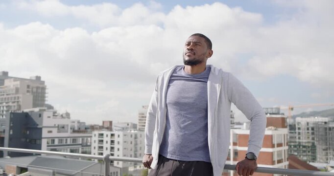 African American man leaning on railing on rooftop, camera moving in, reacting, smiling
