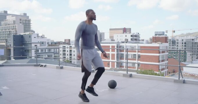 African male starting center, skipping with jump rope on roof in gray, medball right for cardio