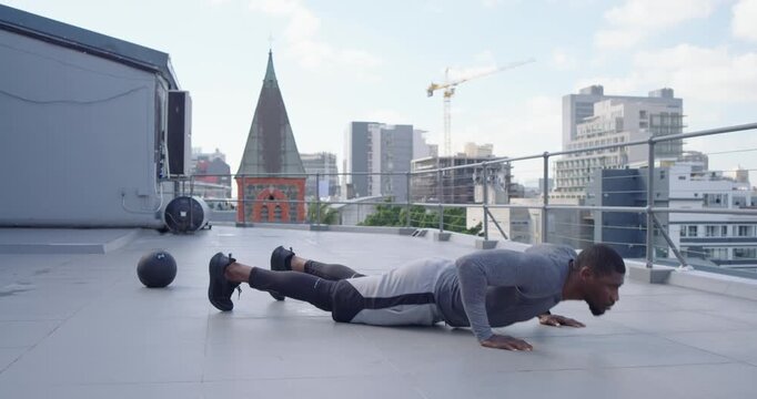 African American man from high plank pressing up tucking knees ending kneeling training on rooftop