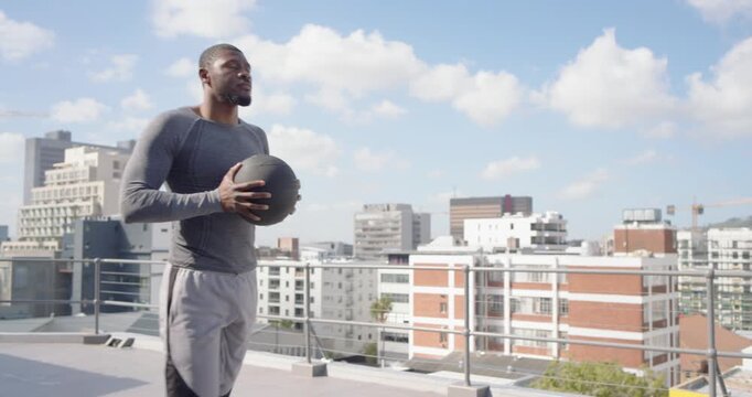 African man in gym gear holding med ball, starting roof routine, striding, bending, resting