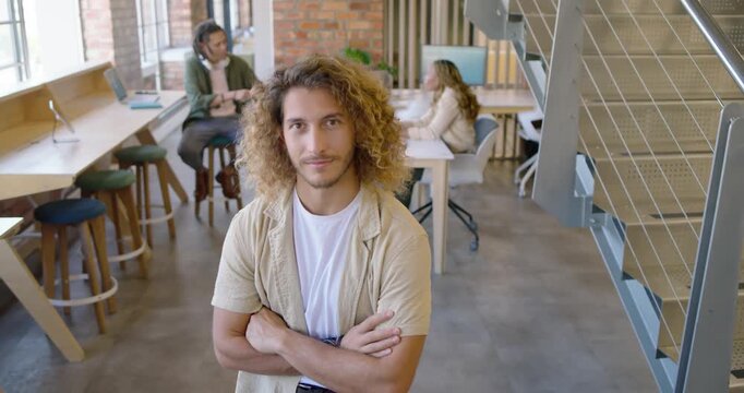 Diverse coworkers talking in office, man standing center watching monitor while smiling at team