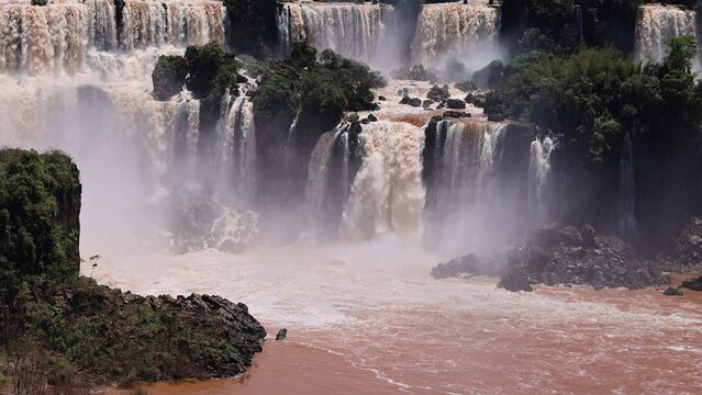 Aerial view of Iguazu Falls with cascading water, lush green vegetation, and rocky cliffs in Foz do Iguacu, State of Parana, Brazil.