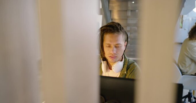 Adult African American man with white headphones slats shifting studying monitor reacting in office