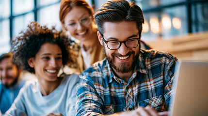 Fototapeta premium Diverse attractive team gathered around a laptop in a bright sunlit office, candid collaboration, large windows and warm wood tones softly blurred behind, teamwork, innovation