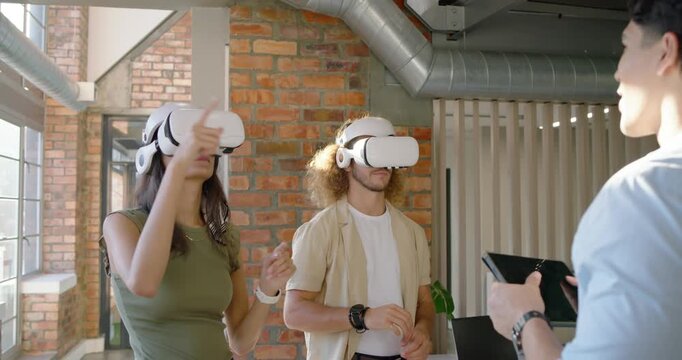 Colleagues adjusting white VR headsets after presenter tapping tablet at office, selecting items