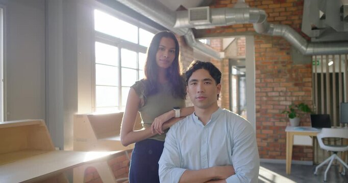 Diverse colleagues posing in loft office, woman resting arm, man crossing arms, sun ending flare