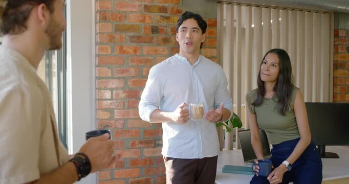 Asian man African American woman replying to left peer starting chat sipping mugs during break