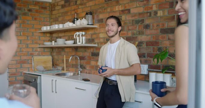Diverse friends talking in kitchen, man leaning at counter with blue mug, smiling at woman speaking