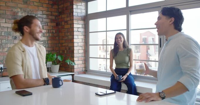 Friends at kitchen island, right friend holding glass telling joke, others laughing then listening