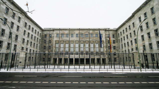 Ministry of Finance building in Berlin. Detlev-Rohwedder-Haus facade shot from across the street behind a security gate under overcast winter skies.