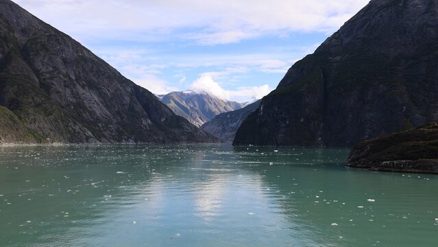 Aerial view of the Inside Passage featuring glacial waters filled with ice chunks surrounded by towering mountains under a blue sky in Skagway, Alaska, United States.