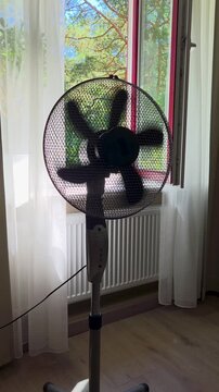 Woman is sitting in front of fan. Hair is blowing by wind. Air conditioning and cooling at home. Summer heat