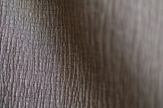 Macro shot of gray polyester fabric texture with textured volumetric weave pattern. Detailed synthetic threads structure with a soft bokeh background