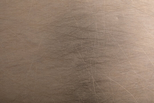 Detailed view of a textured metallic surface showing fine scratches and subtle light reflections.