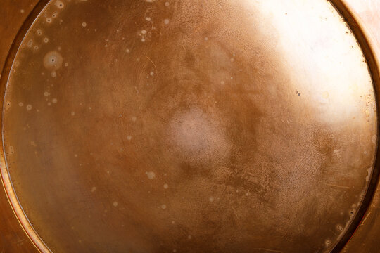 Close-up of weathered copper surface showing patina and circular detail.
