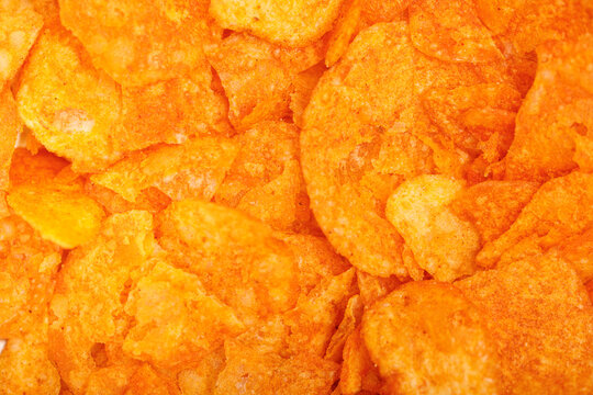 Full frame background texture of golden orange potato chips with savory seasoning.
