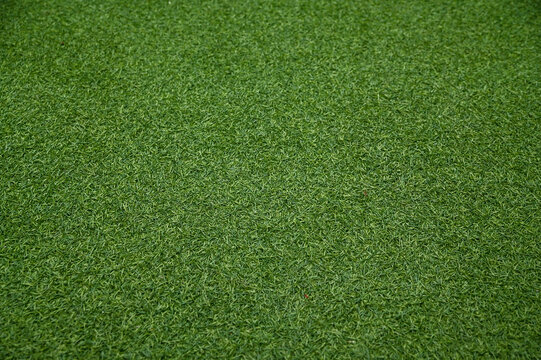 A top-down full frame view of uniform vibrant green artificial grass turf texture.