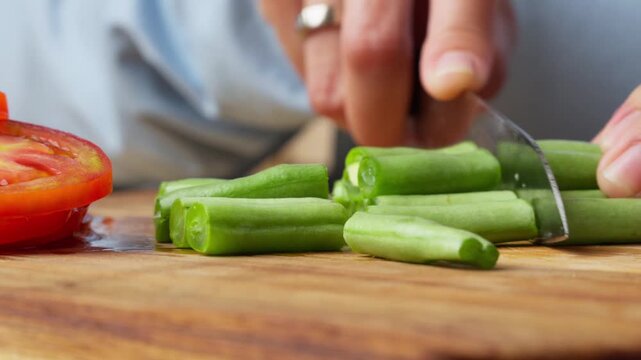 Hands Chopping Fresh Green Beans on a Wooden Cutting Board