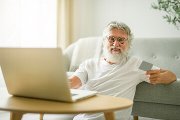 Fototapeta premium senior men using laptop at home apartment with credit card