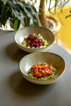 Fresh tuna and salmon bowls with green cucumber and avocado served in a cafe