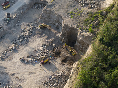 Aerial view of Sand and Stone Quarry with excavators and dump trucks working in the mining site in Manisrenggo, Central Java, Indonesia.