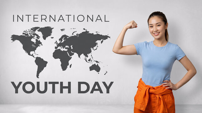 Confident young Asian woman flexing her bicep muscle in a powerful pose celebrating International Youth Day. She wears casual blue t-shirt and orange pants standing in front of world map background.