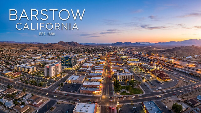 The historic town of Barstow, California, captured in an aerial view at sunset, with a prominent rail yard