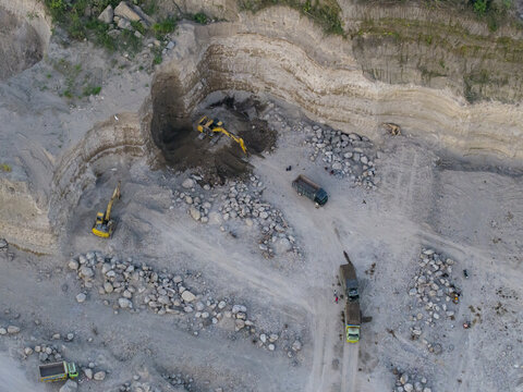 Aerial view of Sand and Stone Quarry with excavators and trucks operating in the mining site in Manisrenggo, Central Java, Indonesia.