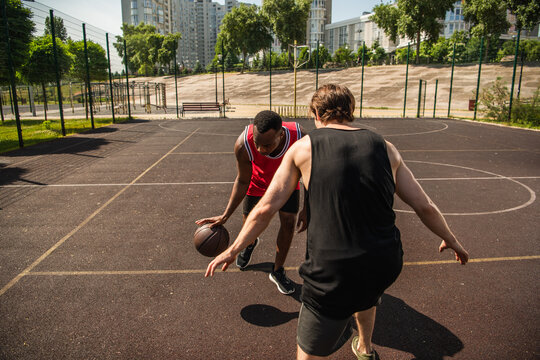 Multiracial friends enjoy summer streetball on an outdoor court