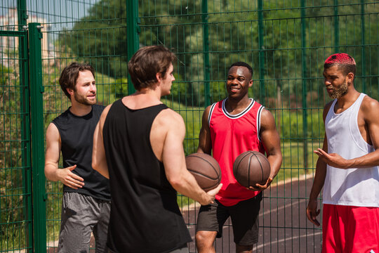 Multicultural friends enjoying outdoor basketball in the summer sun