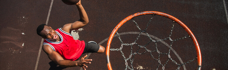 Young athletic man performs a slam dunk on an outdoor basketball court © LIGHTFIELD STUDIOS