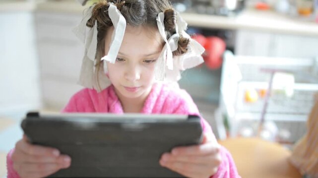 Small beautiful girl plays on tablet computer