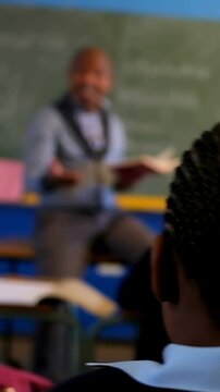 Vertical video: Raising plaid shirt student answering teacher gesturing in class with book at board