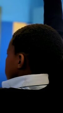 Vertical video: Camera pulling back, boy in white shirt raising hand to answer in class at board