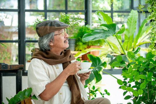 Happy retired man taking a coffee break in a bright green living space reflecting comfort mindfulness healthy lifestyle and retirement happiness.
