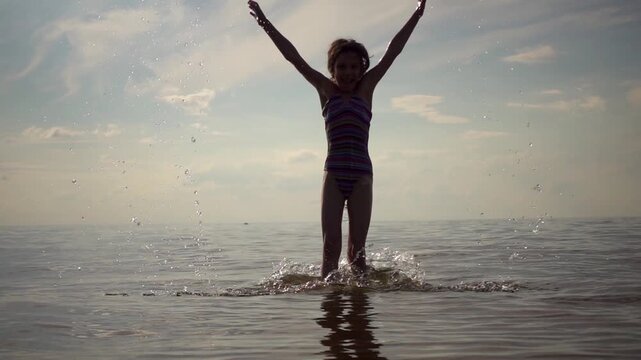 Beautiful little girl holds up spray in sea