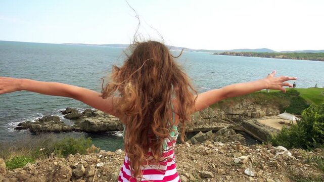 Little girl on rocky shore of sea