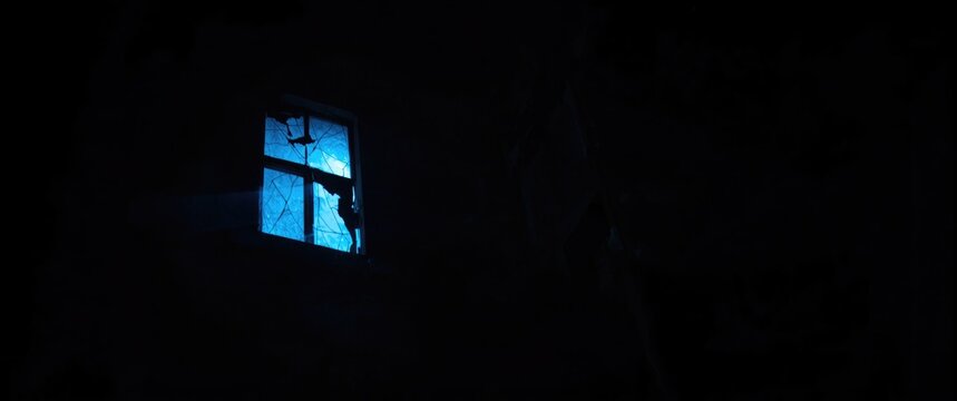 Broken window with blue light in a dark room