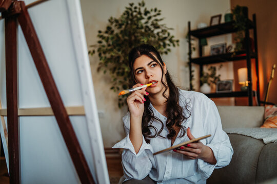 Artist creating painting, thoughtfully composing new ideas for canvas