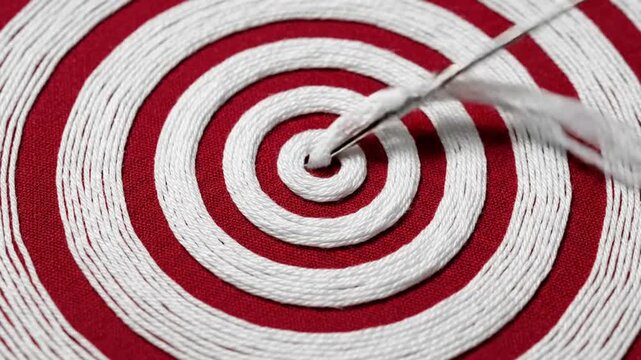 Close up of needle embroidering white concentric circles on red fabric.
