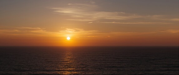 Fototapeta premium Sunset over the ocean with calm water and clouds