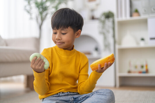 Smiling asian little boy squeezing squishy toys for relaxation and focus, Sensory play, fine motor skills, emotional child development, therapeutic learning, stress relief and healthcare lifestyle