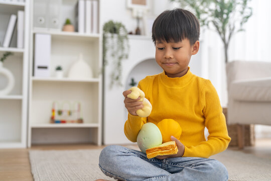 Smiling asian little boy squeezing squishy toys for relaxation and focus, Sensory play, fine motor skills, emotional child development, therapeutic learning, stress relief and healthcare lifestyle