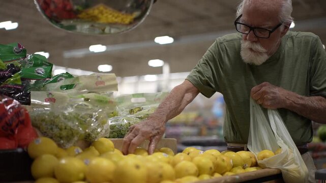 Elderly man shops for fresh fruits and vegetables in grocery store, focusing on selecting lemons and placing them in his bag